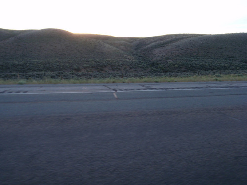 The sun is hiding behind a hill.